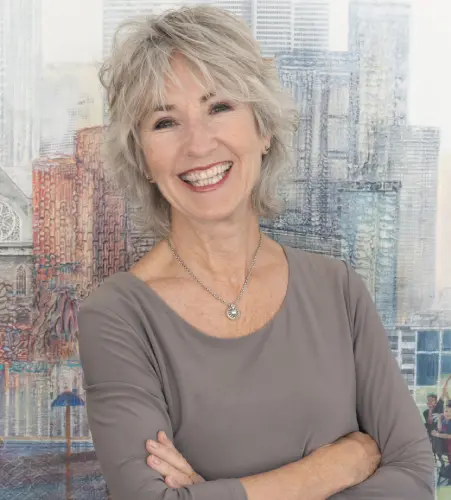 A woman with her arms crossed in front of a city.