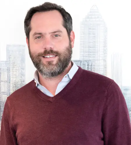 A man in a red sweater standing next to a city.