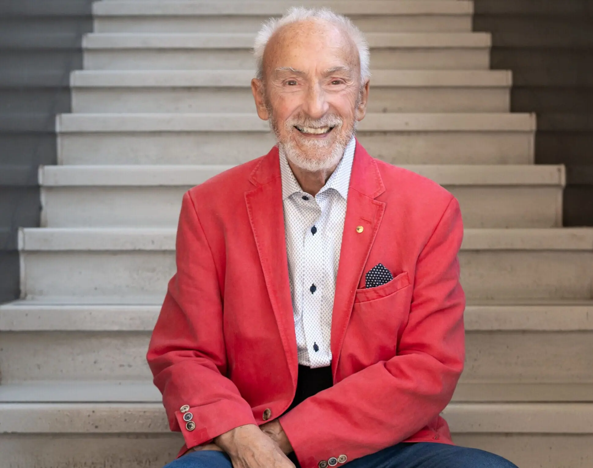 A man in a red jacket sitting on steps.