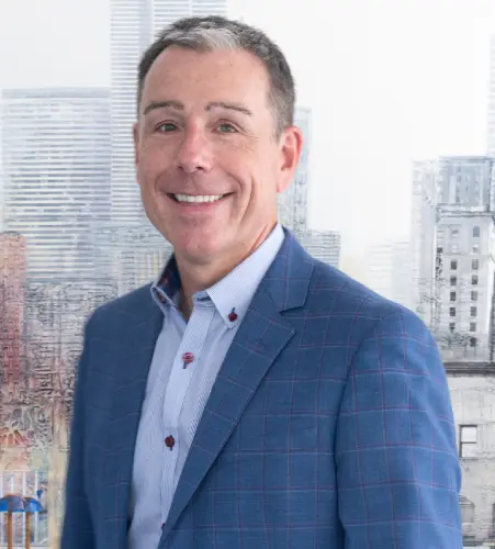 A man in a blue suit standing next to some buildings