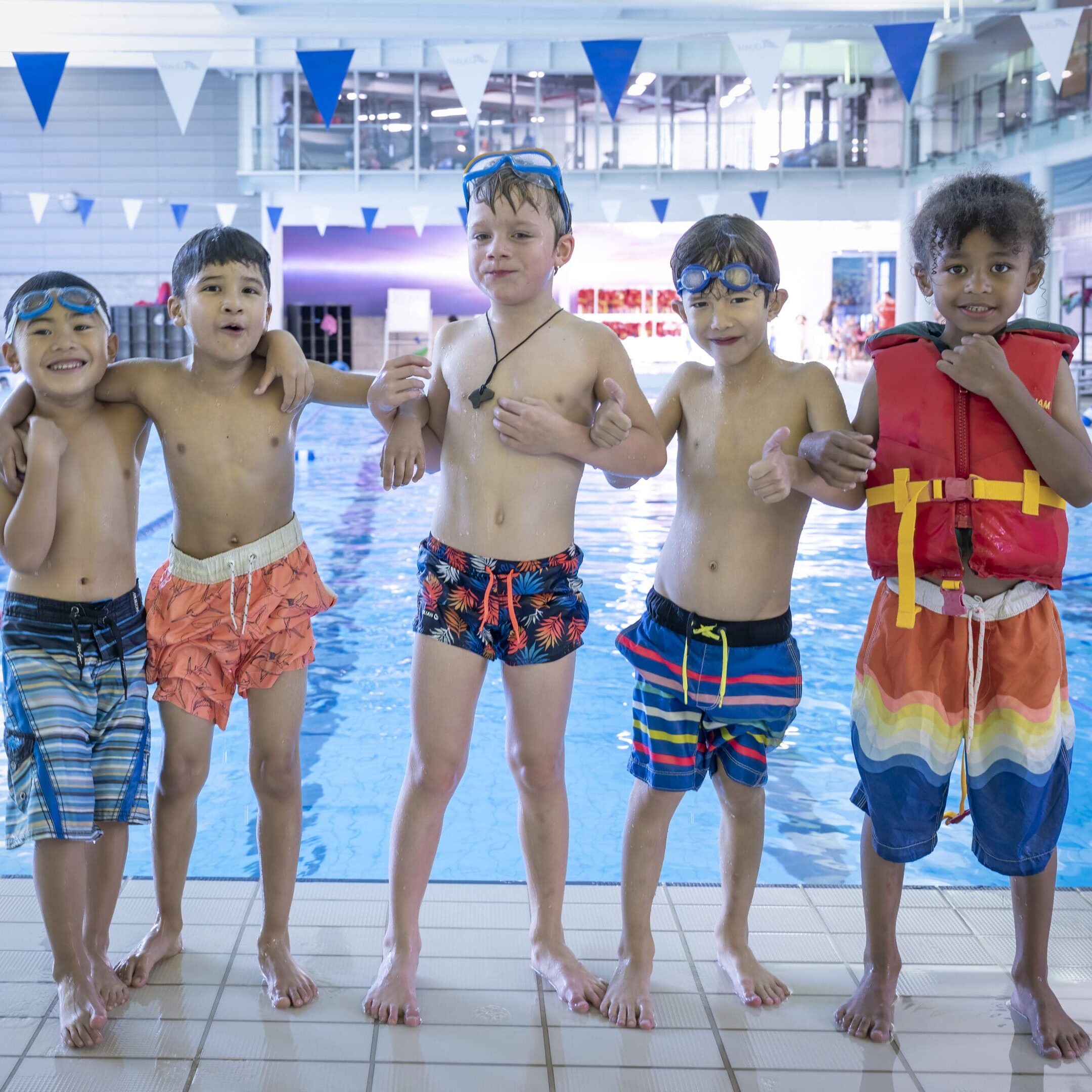 A group of young boys standing in front of an indoor pool.